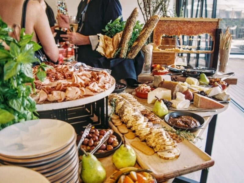 Reichhaltiges Frühstücksbuffet mit Käse, Aufschnitt, Brot, Obst und Kräutern