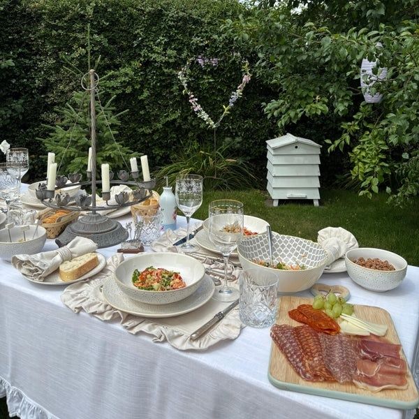 Gedeckter Gartentisch mit Brot, Aufschnitt, Salat und regionalem Buffetgeschirr